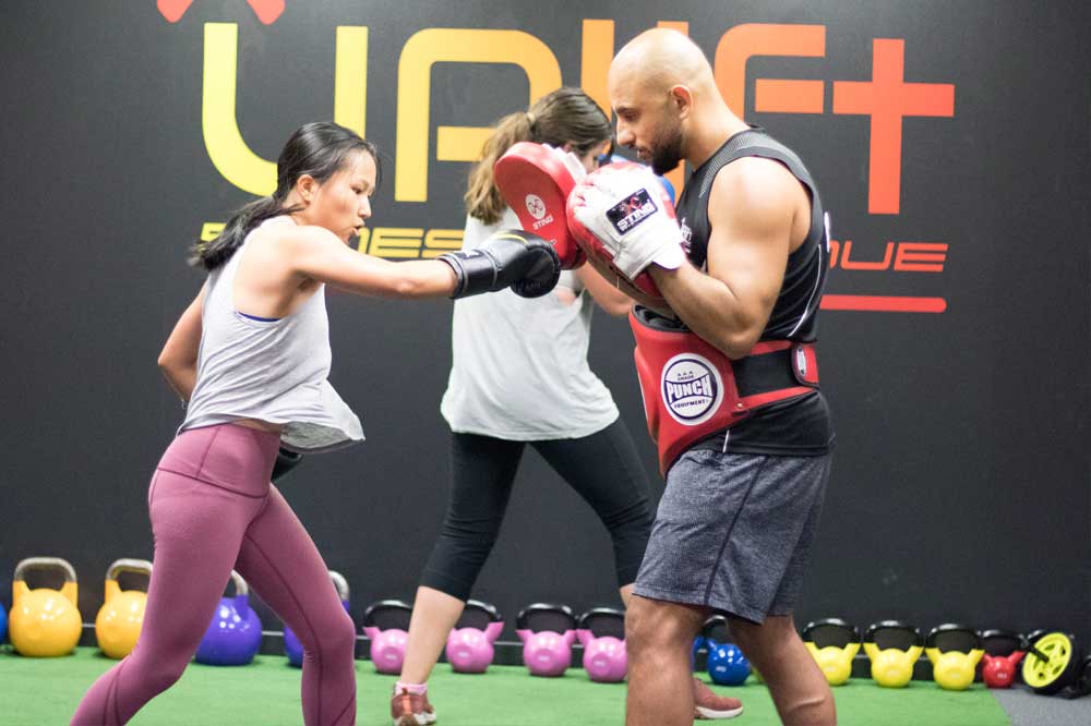 Coach holding pads for a boxing combination in Punch Fit